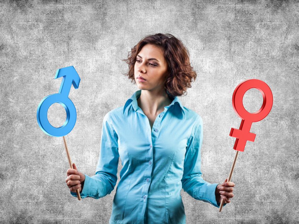 Woman holding masculine and feminine gender signs