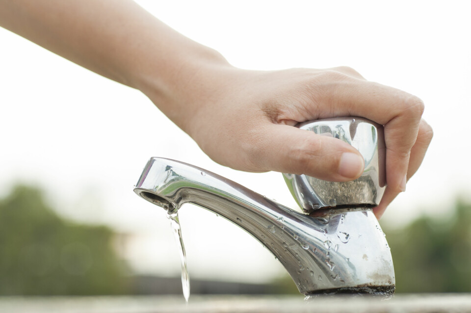 A photo of a woman turning off a tap to save water