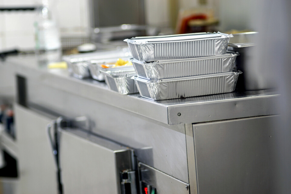 A professional restaurant kitchen packages up food in takeaway boxes