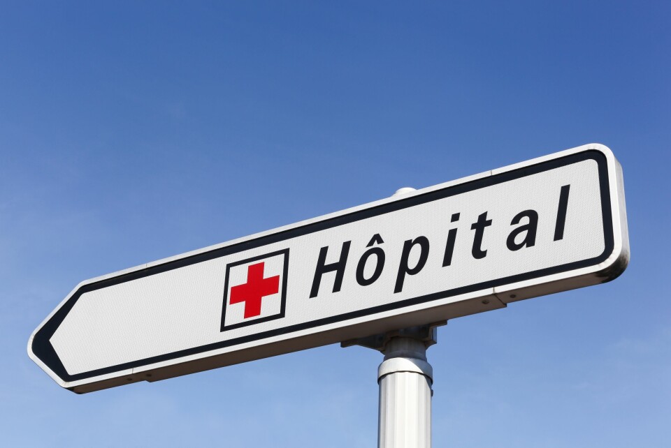 A photo of a sign reading Hopital (hospital) in French against a blue sky