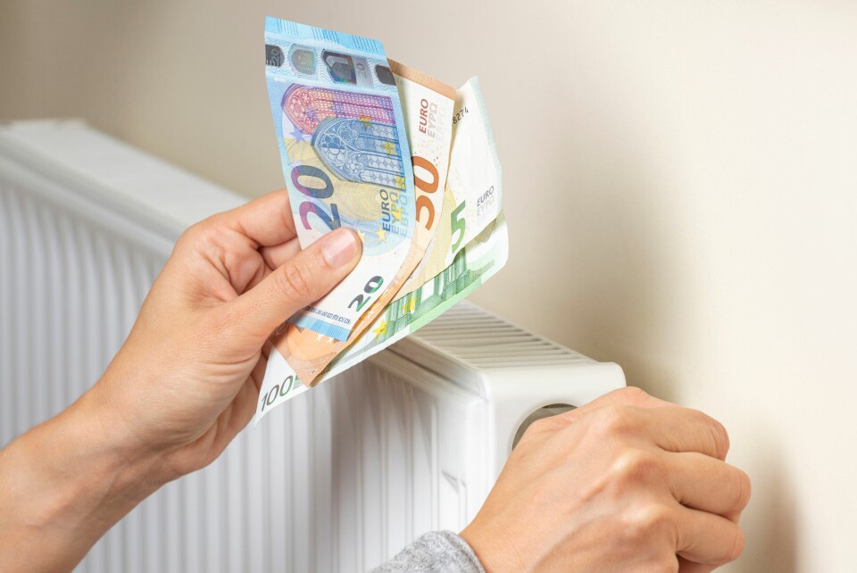 A photo of someone holding euros above a radiator and turning it down, to show rising costs of heat