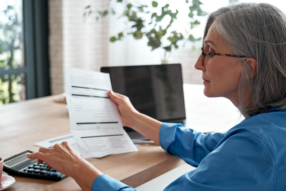 A older woman holding a piece of paper and working something out on a calculator