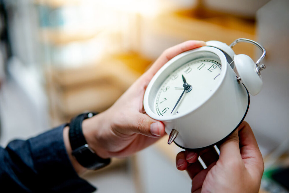 A photo of someone turning a clock back to show October daylight savings change