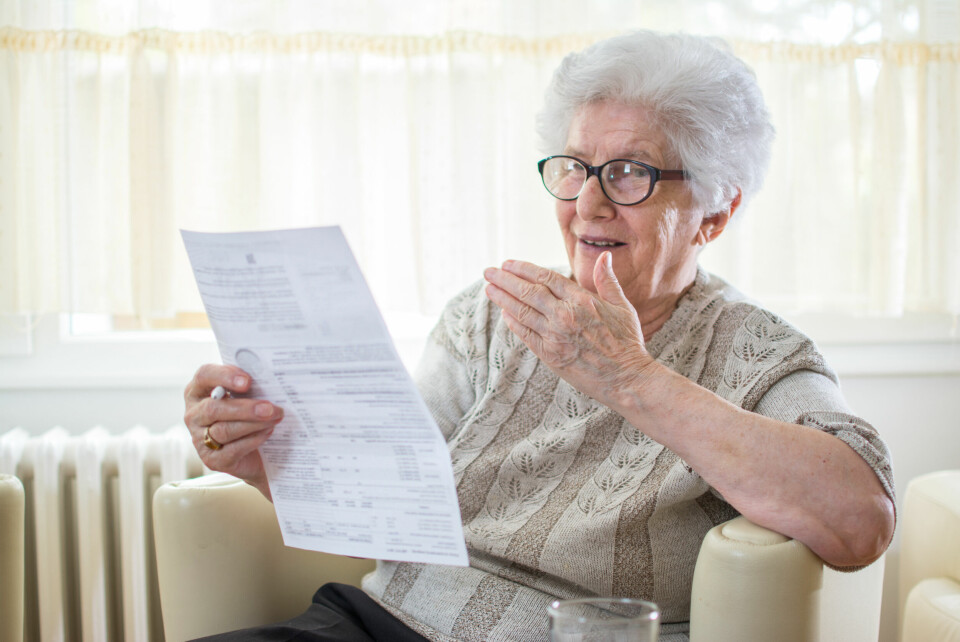 An older woman looking shocked while looking at a letter