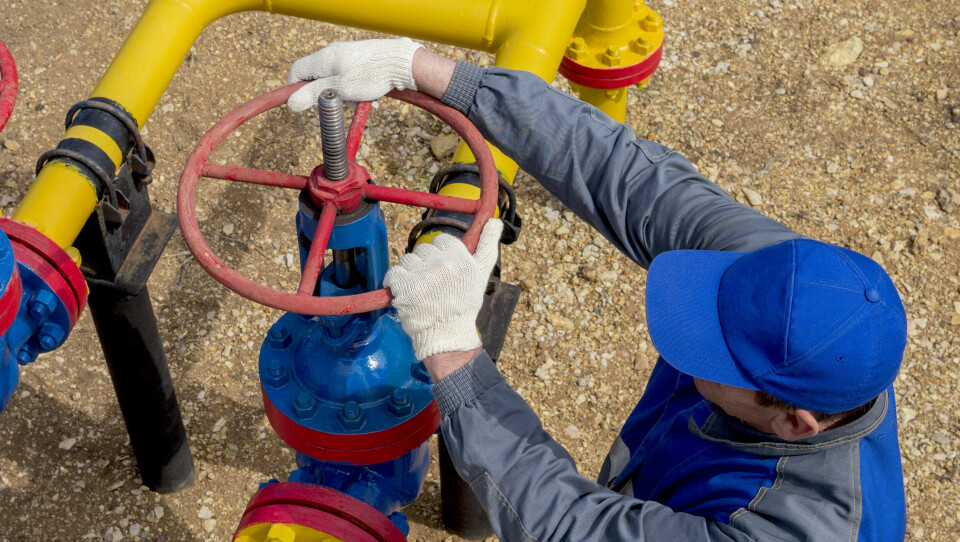 A worker shutting off a gas transport pipe