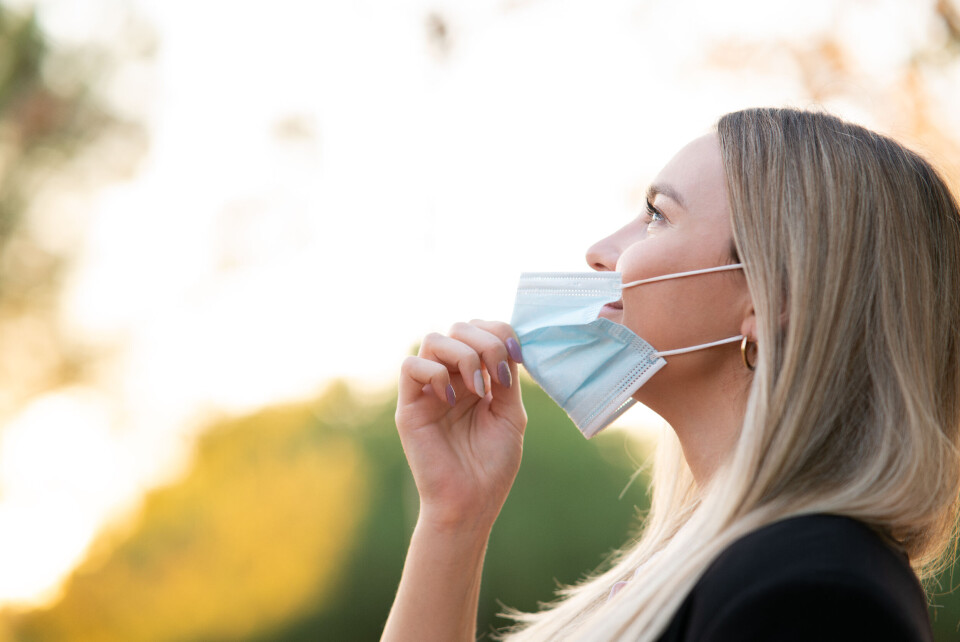 ArekSanz / Shutterstock A women taking off her mask outdoors