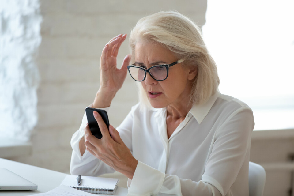 An older woman looks at a smartphone in shock