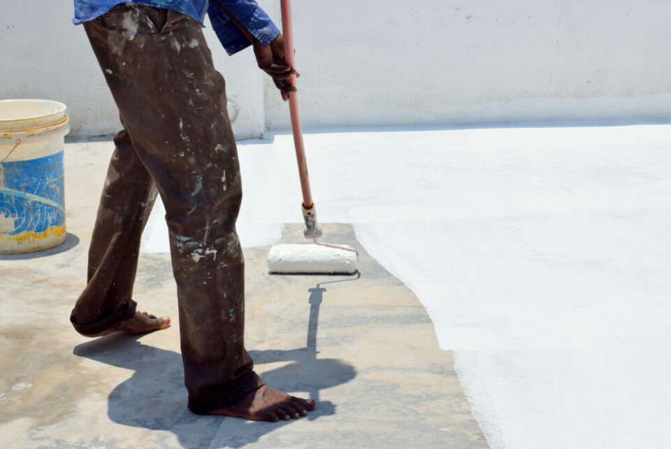 A photo of a man painting outside white