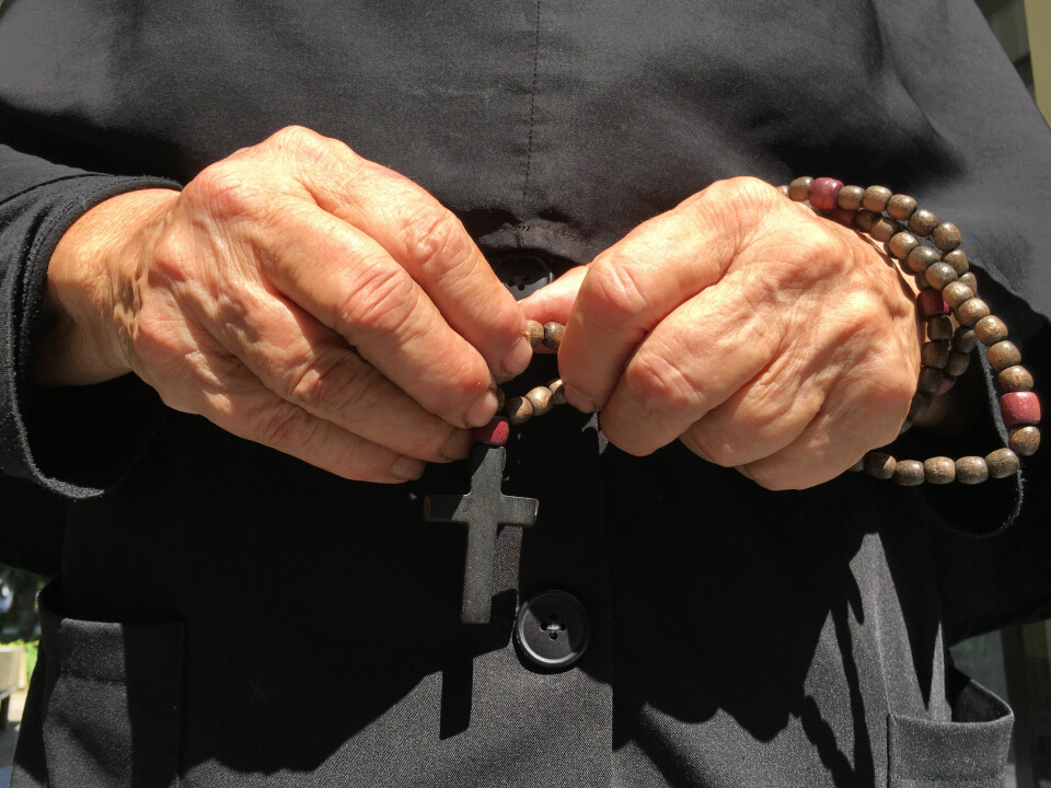 An elderly nun holds rosary beads