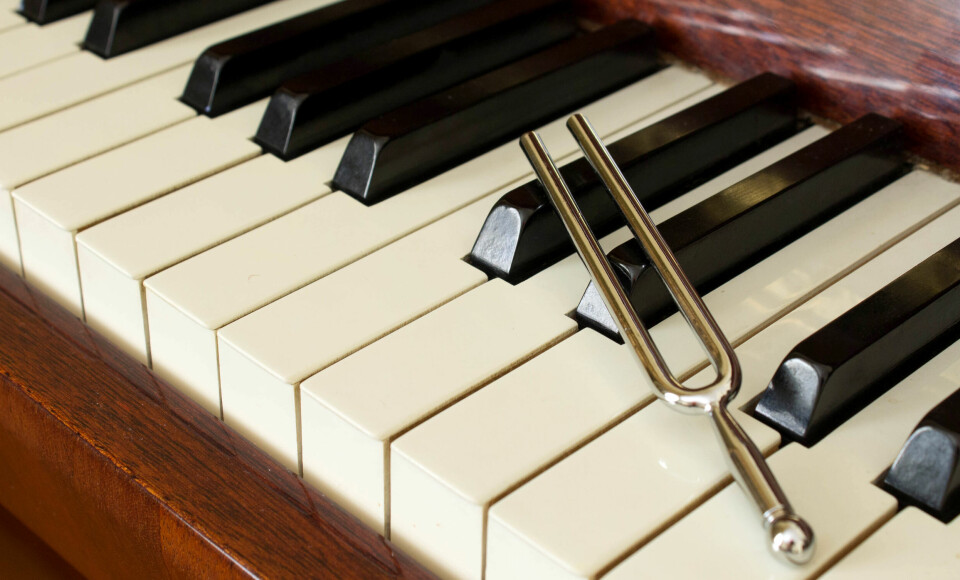 An image of a tuning fork resting on a piano