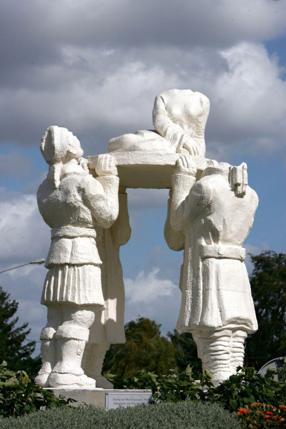 Four soldiers hoisting a lady on a plinth