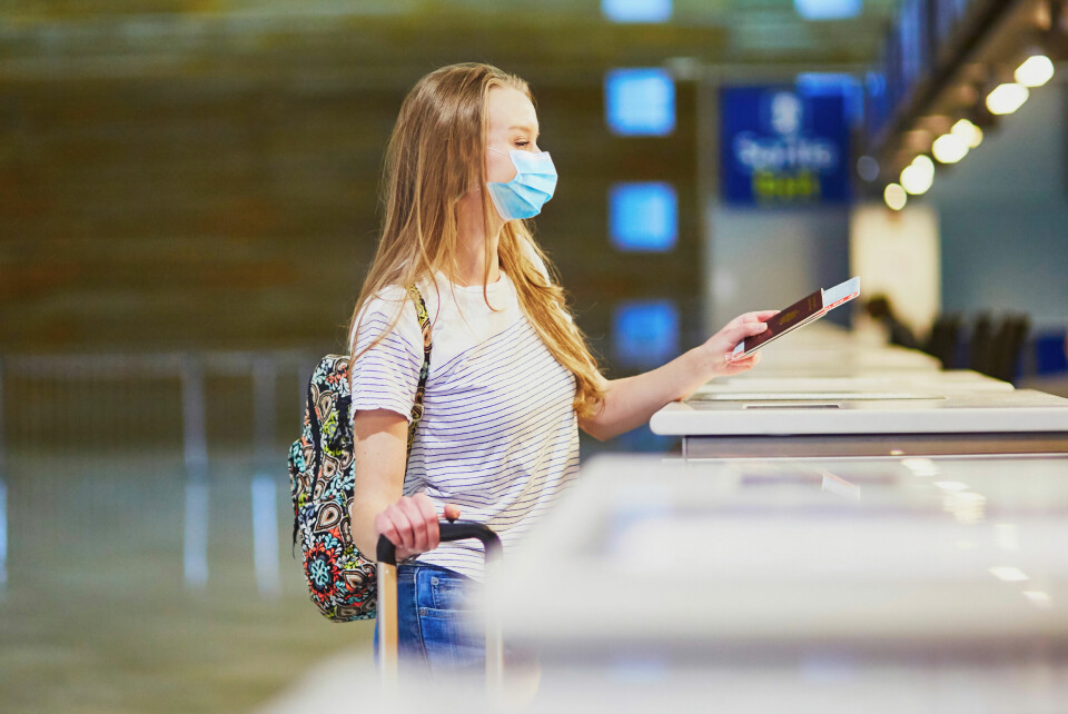 an image of a girl wearing a face mask handing over her passport at airport check-in