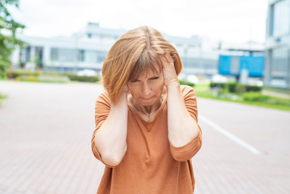 A woman covers her ears in the street