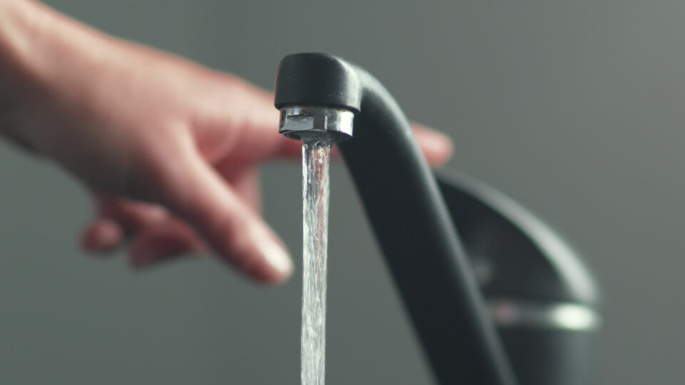 A photo of someone using a tap with water flowing out of it