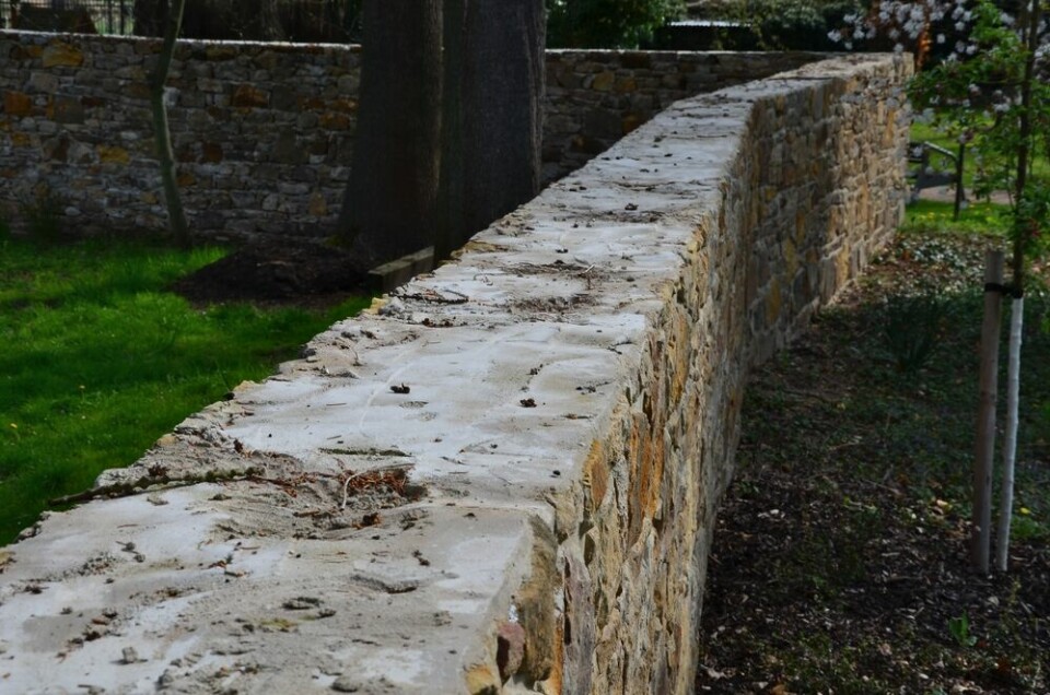 A photo of an old stone wall alongside a pathway