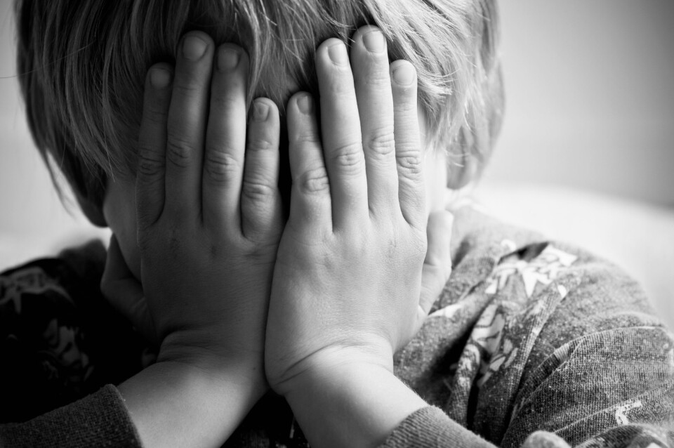 A photo of a child covering their face with their hands to show distress