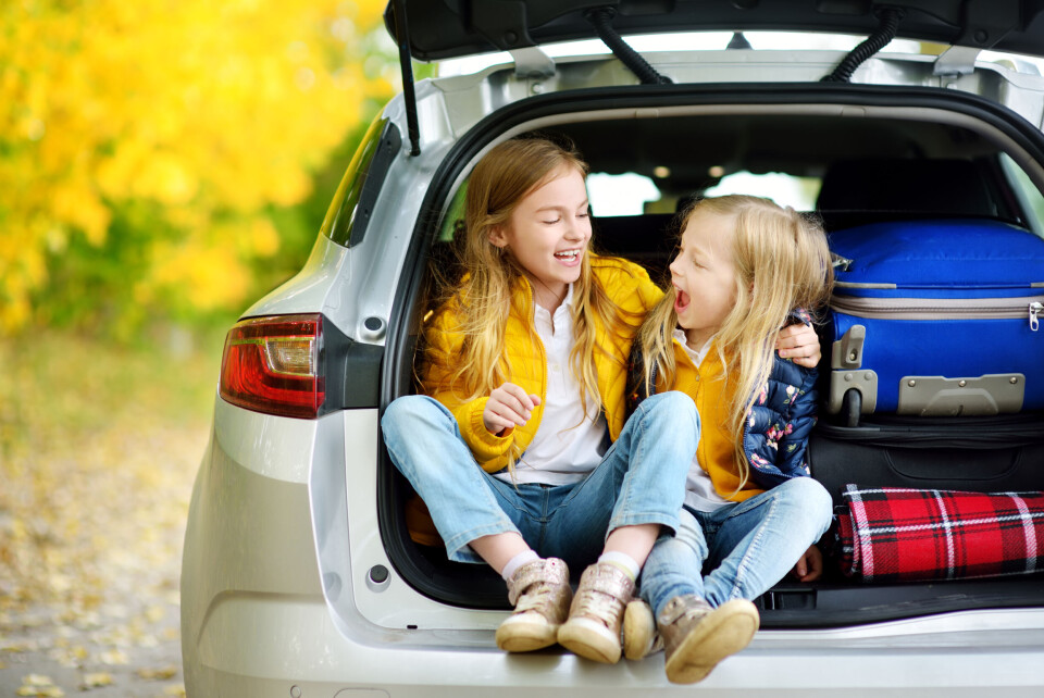 MNStudio / Shutterstock Two young kids looking happy in the back of a car preparing to go on holiday
