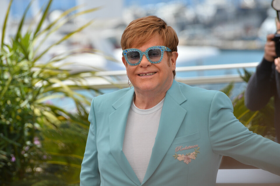 A photo of Elton John wearing a blue suit and glasses in Cannes, France
