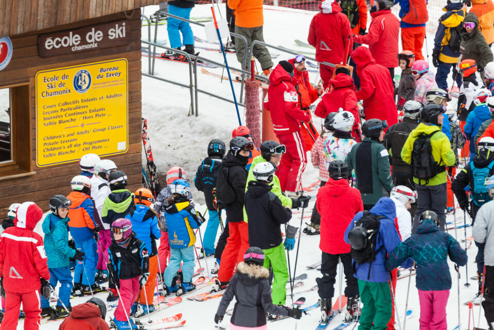 A view of a busy ski school area with children and adult skiers in France