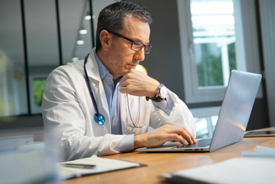 A doctor at a computer looking puzzled