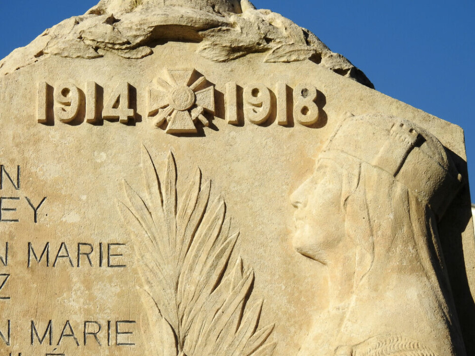 A World War One memorial carving with years and woman figure