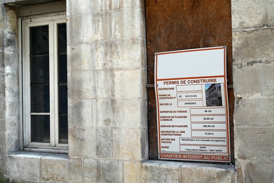 A view of a Permis de Construire permit on a boarded-up window on a building