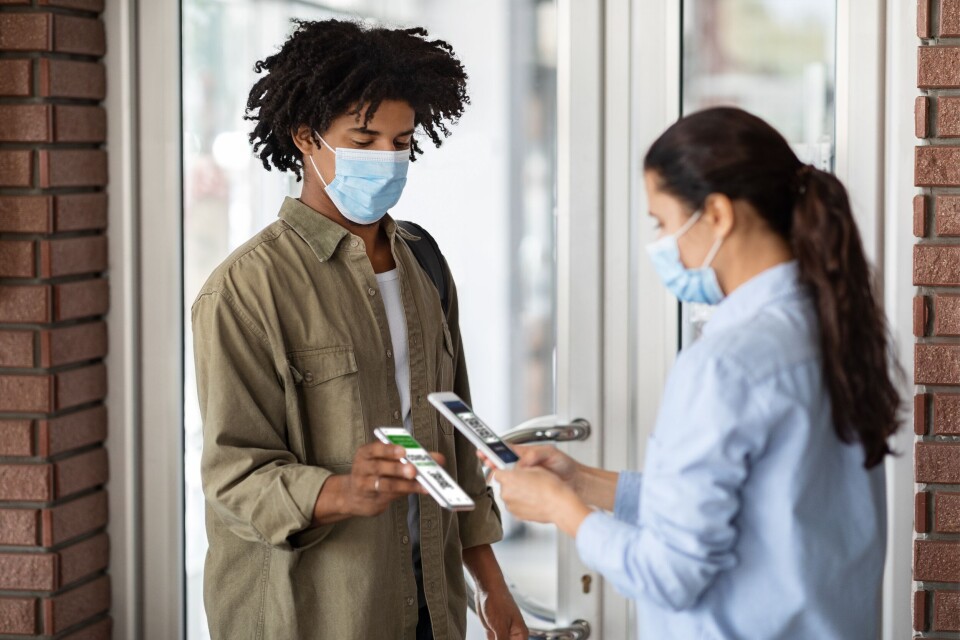 Prostock-studio / Shutterstock An image of a man having his vaccine pass scanned by a waitress