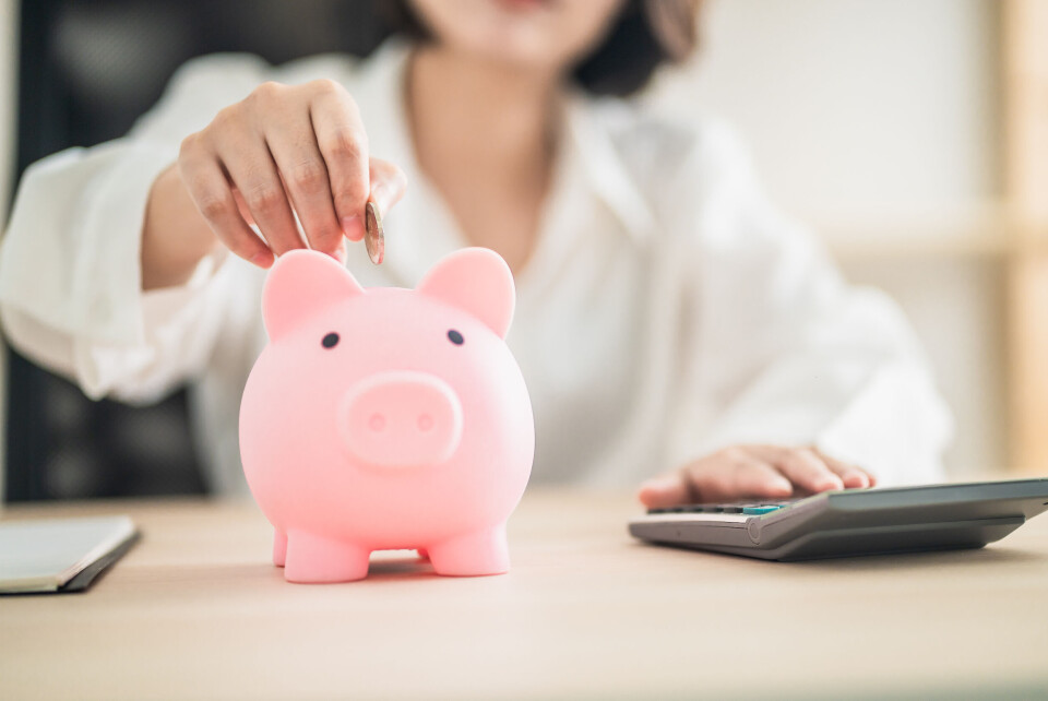 Gumbariya / Shutterstock A woman putting coins into a piggy bank to show a concept of savings