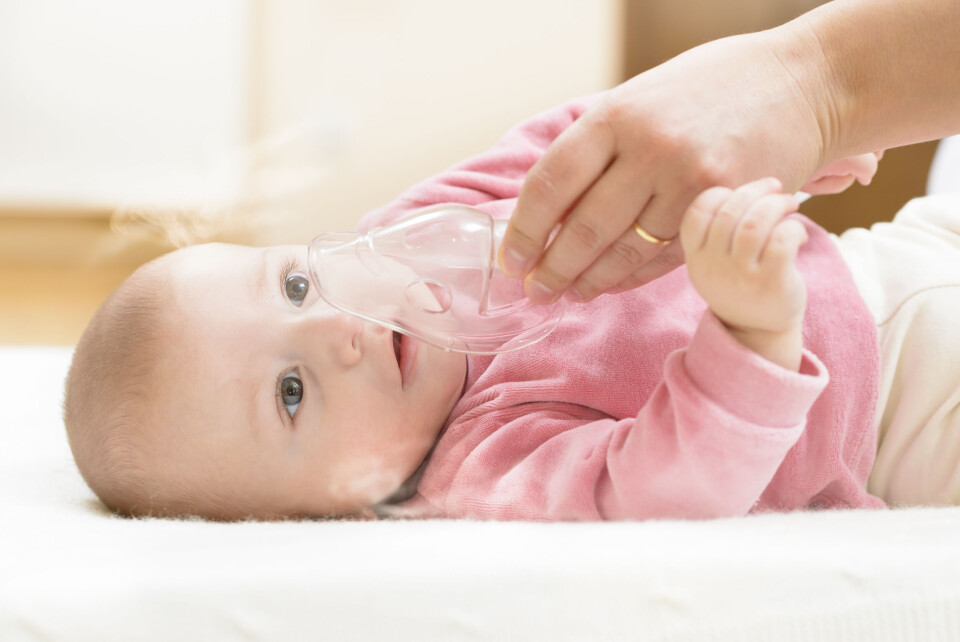 A photo of a young baby with a breathing mask being placed over her face