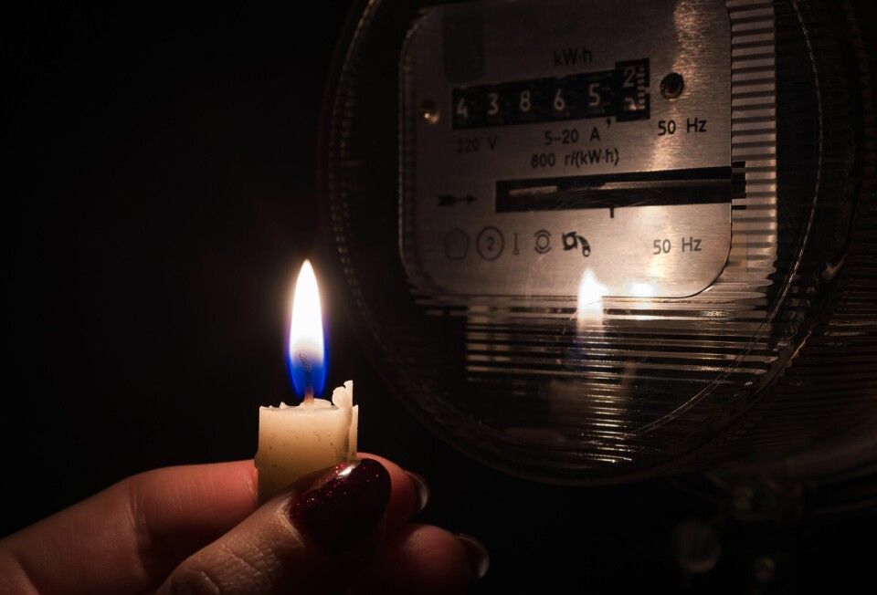 A photo of someone holding a candle up to an electricity meter