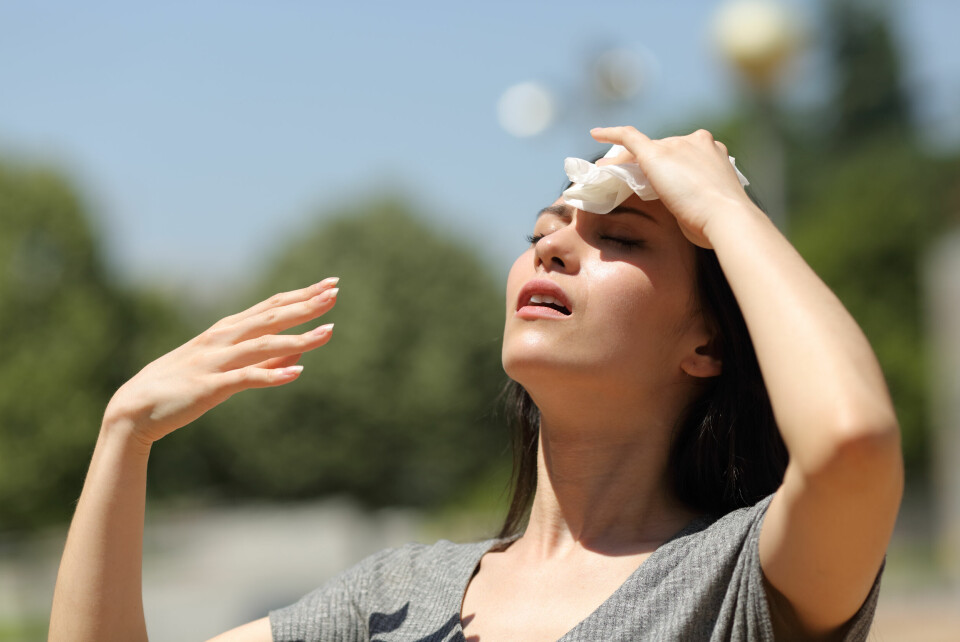 A photo of a woman wiping sweat from her forehead on a hot day