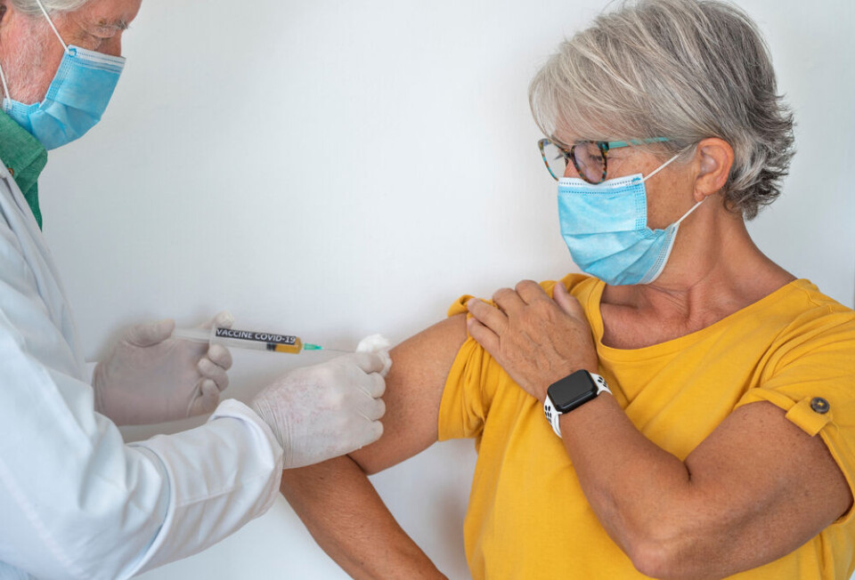 An older woman receiving a vaccination, wearing a mask