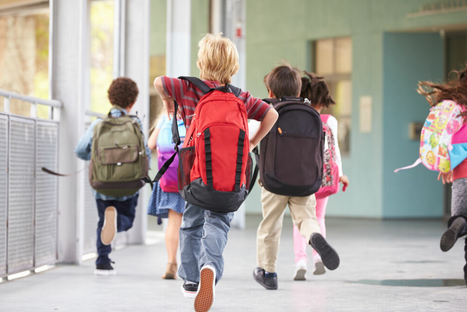 Kids with school backpacks running into school