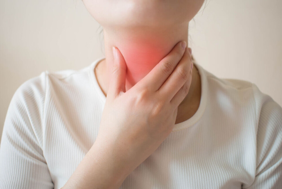 A woman holding her throat, which is coloured red to show pain