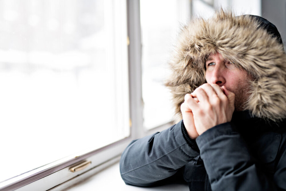 A photo of a man wearing a thick coat indoors looking cold