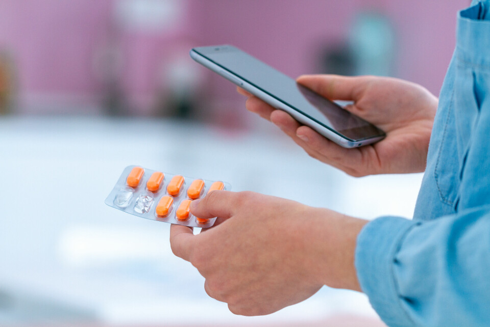 A view of a patient holding a blister pack of tablets and their phone, to show digital records
