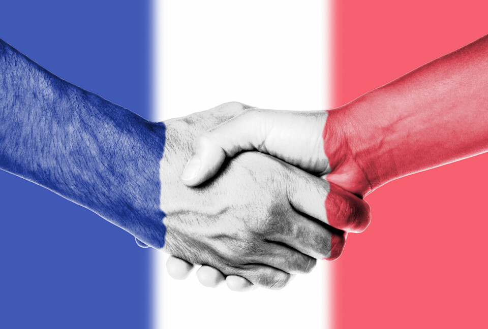 Shaking hands with a background of French flag colours