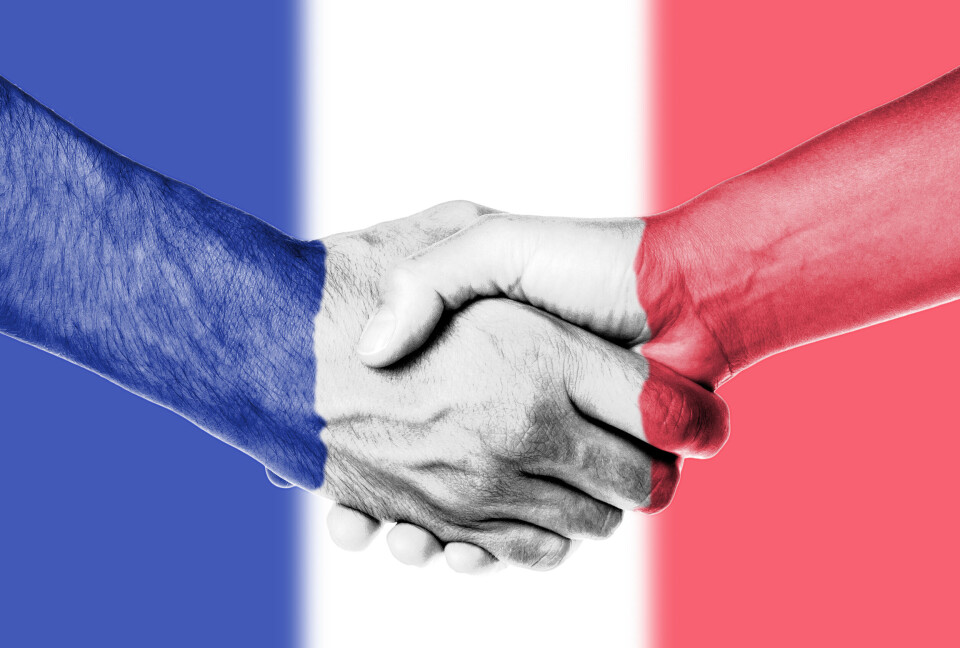 Micha / Shutterstock Shaking hands with a background of French flag colours