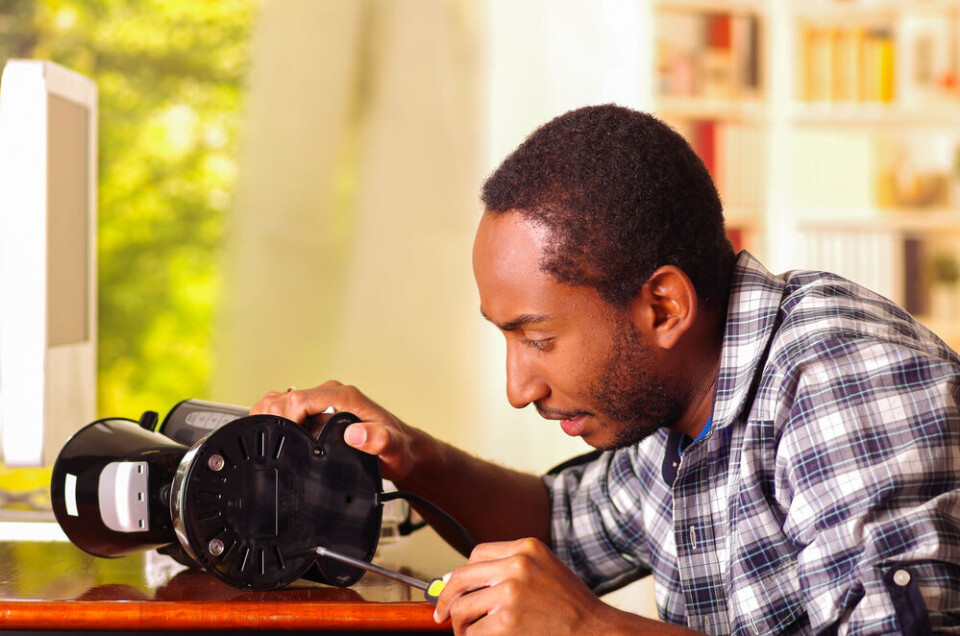 A view of a man repairing the underside of a coffee machine with a screwdriver