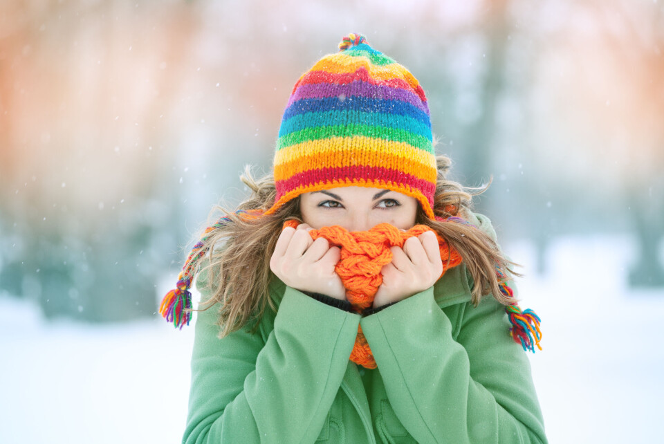 taramara78 / Shutterstock A woman in a bright scarf and hat bracing against the cold