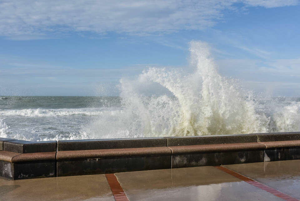 A wave crashing over a sea wall in France