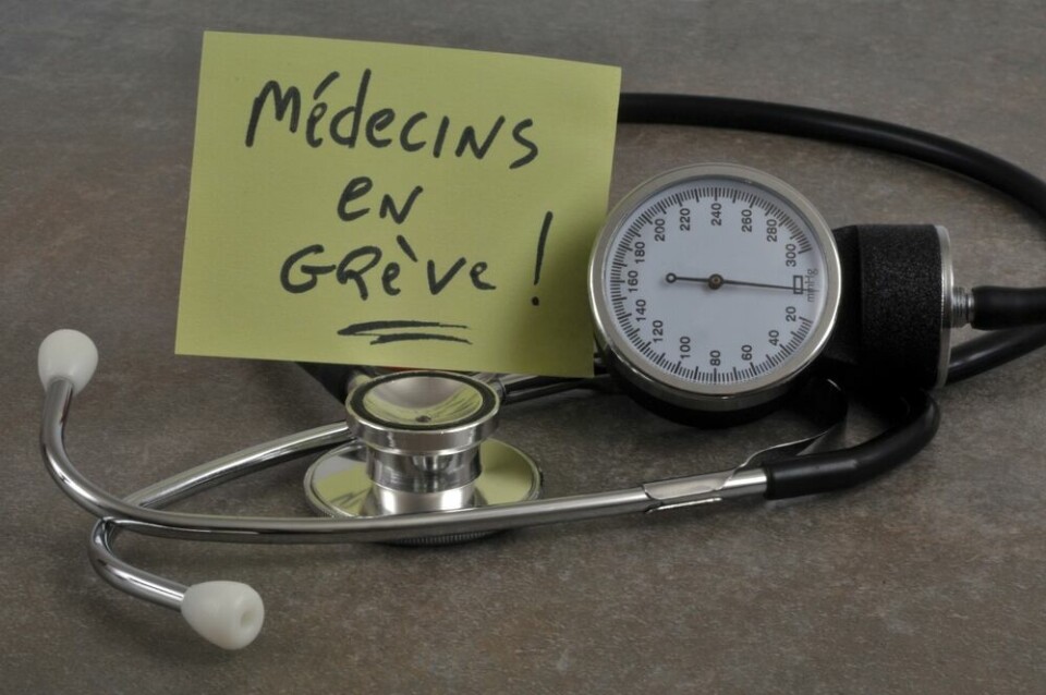 A view of a GP stethoscope and a Post-It note saying ‘Doctors on strike’ in French