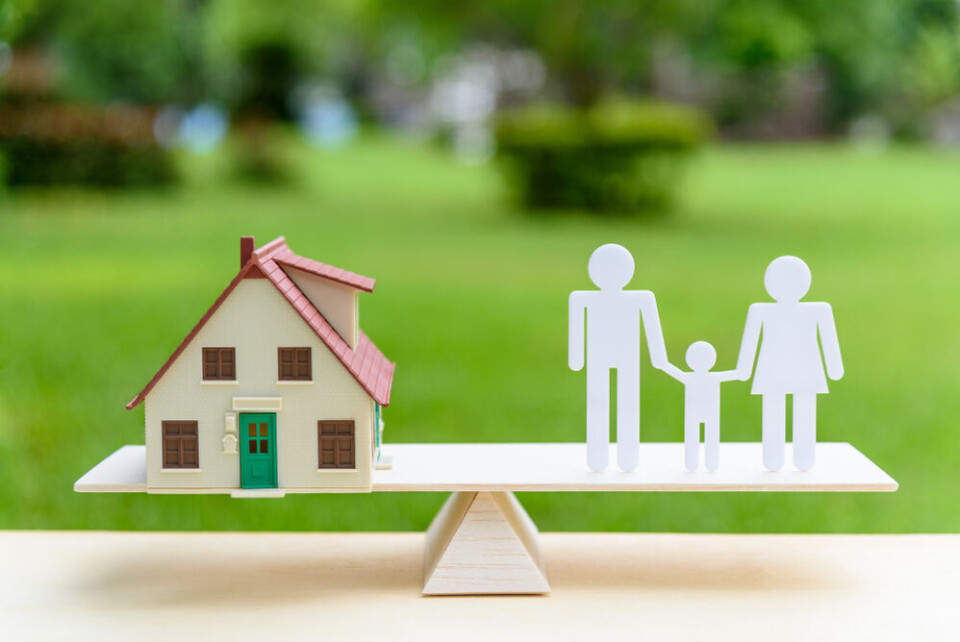 A photo of a model see-saw with a model house and cut-outs of a family