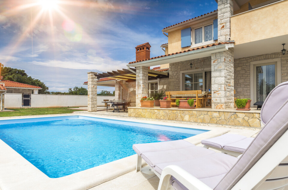 A view of a private pool by a house on a sunny day