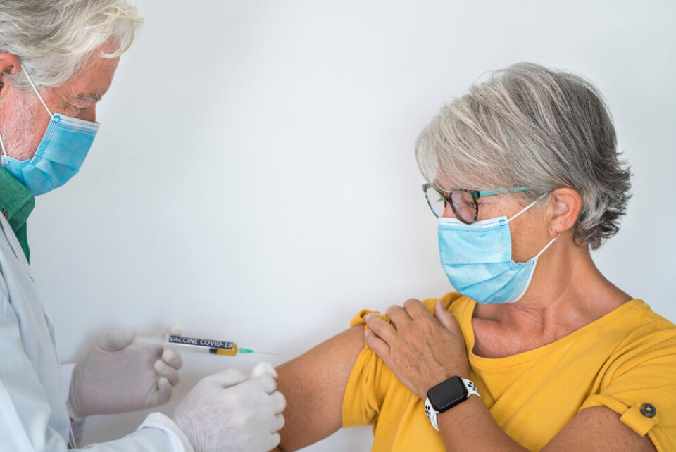 An older woman receiving a vaccination, wearing a mask