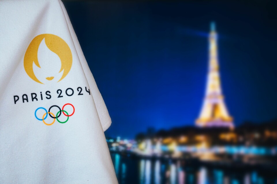 A photo of the Paris 2024 logo and flag against a backdrop of Paris