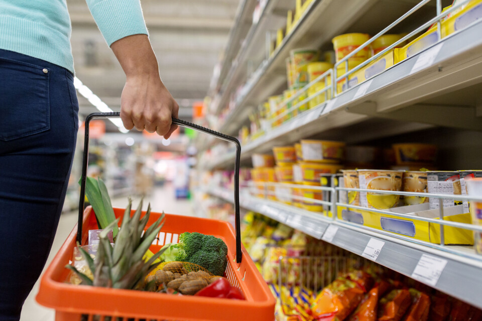 A photo of a woman carrying a basket of items in a supermarket