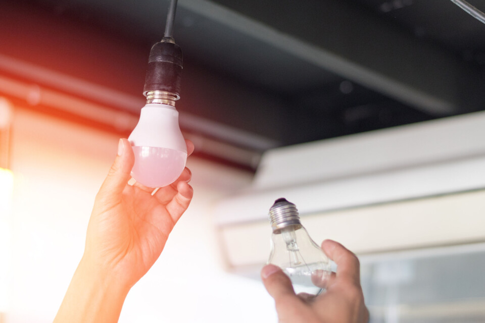 A person changes an old lightbulb for a new LED one