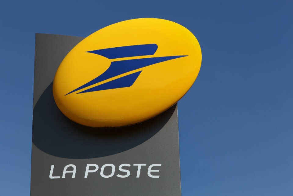 A photo of the La Poste logo on a large sign against a blue sky