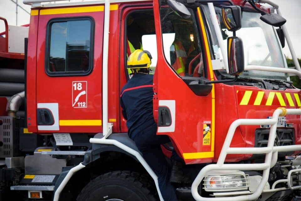 A photo of a firefighter getting into a fire truck in France, with the emergency numbers 18 and 112 on the side